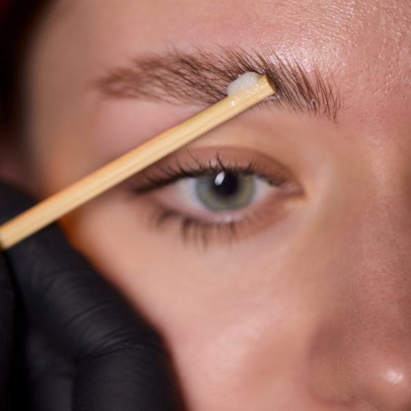 This is a closeup view demonstrating an eyebrow grooming technique that utilizes a wooden stick for precision